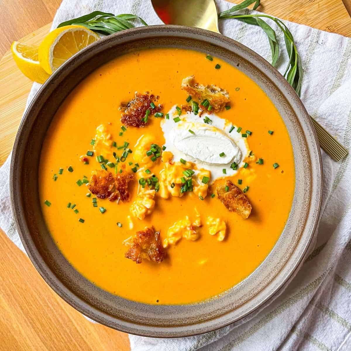 Lobster bisque in a bowl on a table and garnished with cream and crotons.