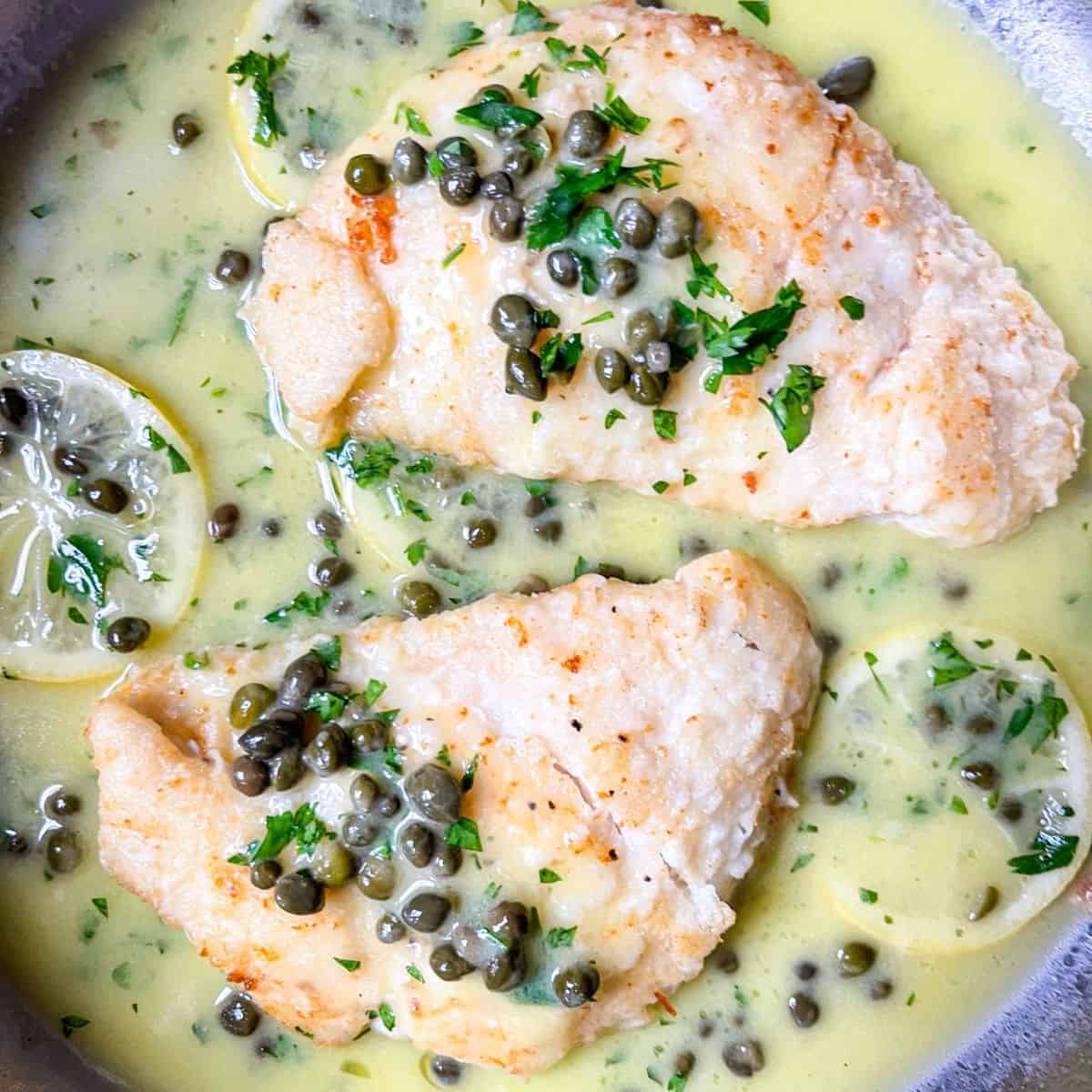 2 pieces of halibut cheeks in lemon piccata sauce.