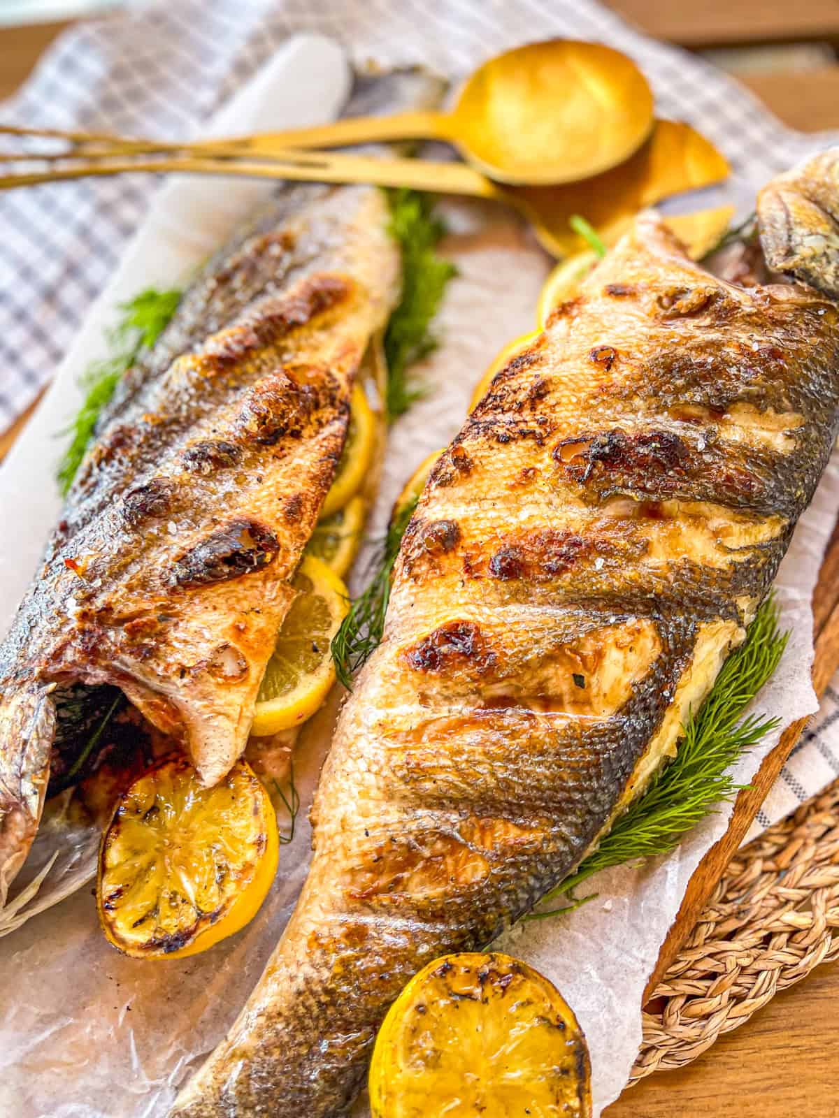 2 poissons entiers grillés sur une assiette à côté d'une cuillère.