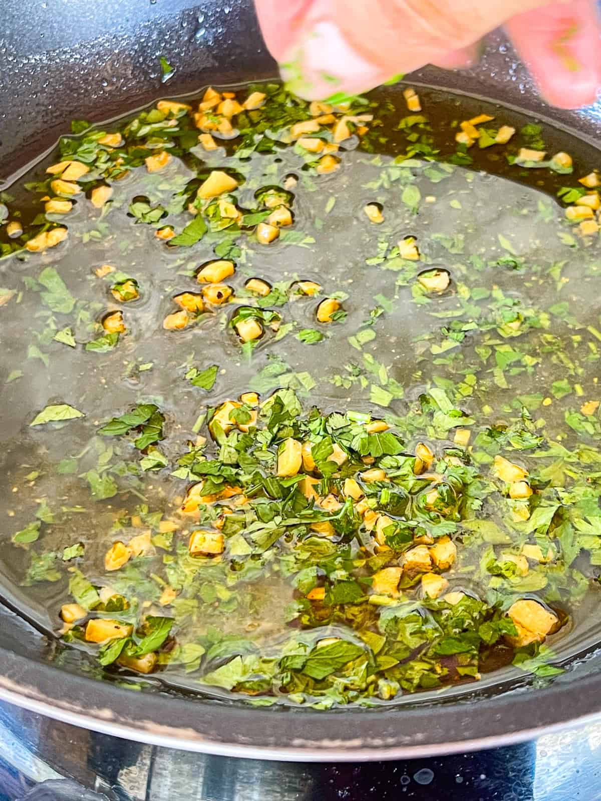 Sauce à l'ail et aux herbes préparée dans une poêle.