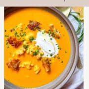 Bisque de homard dans un bol sur une table et garnie de crème et de crotons.