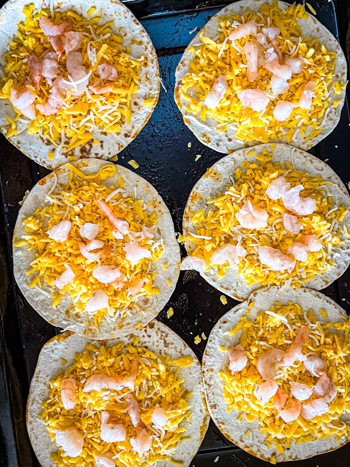 crevettes et fromage répartis sur 6 tortillas pour faire des quesadillas.