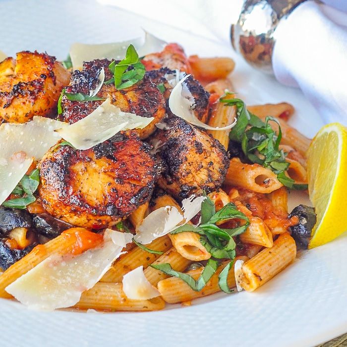 Pétoncles Cajun Puttanesca photo en gros plan d'une seule portion sur une assiette blanche