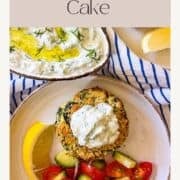 Morceau de gâteau de poisson au tzatziki sur une assiette de légumes.