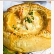 épingle Pinterest montrant une bisque de crevettes dans un bol de pain croustillant garni de dés de ciboulette.