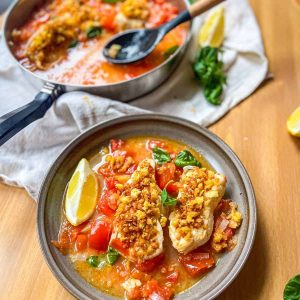 Poached fish in spicy tomato broth in a bowl and a pan.