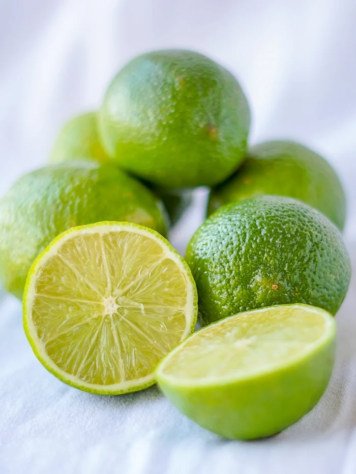 photo de citrons verts sur fond blanc avec une coupe pour révéler l'intérieur.