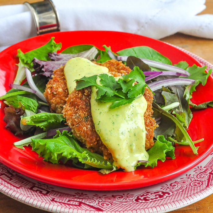 Gâteaux de crevettes avec photo d'aïoli au citron vert affichée sur une assiette rouge avec de la salade