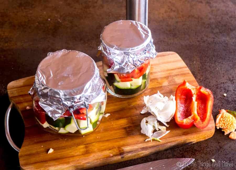 Bocaux remplis de légumes et de saumon, recouverts de papier d'aluminium.