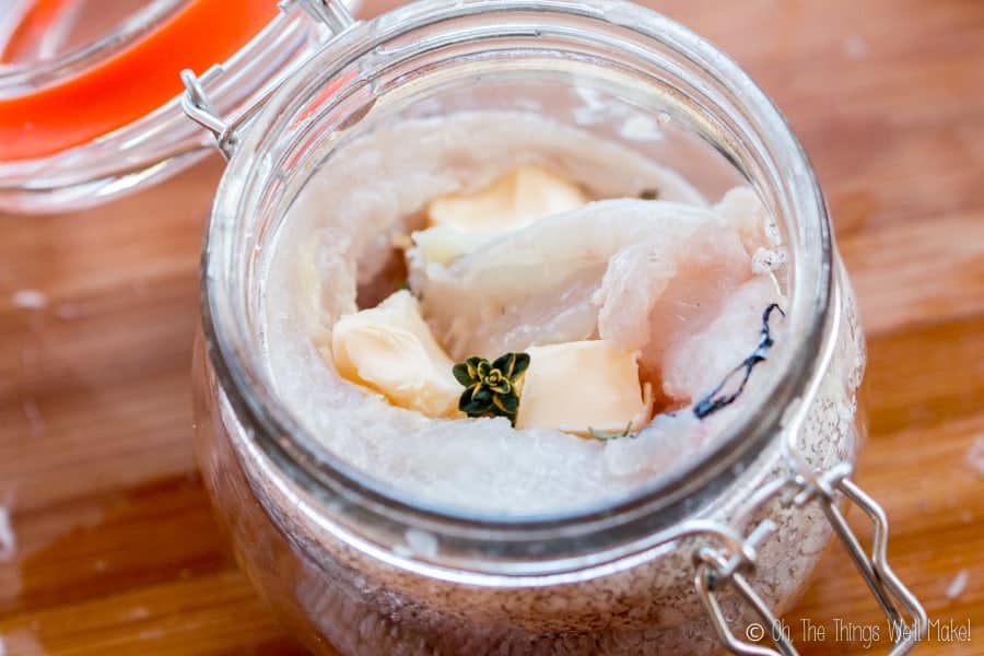 Vue aérienne du merlu dans un pot avec du beurre et du thym, prêt à être cuit au lave-vaisselle.