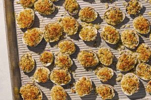 Clams oreganata spread evenly on a sheet pan.