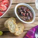 Calamares al vino tinto, ou calamars braisés au vin rouge, vus d'en haut, servis avec du pain et des crevettes rouges