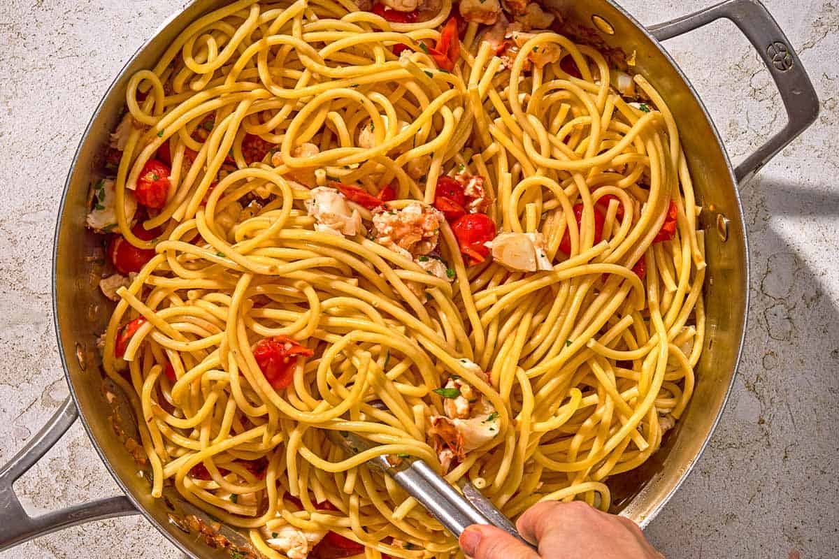 Les pâtes au homard étant mélangées dans une poêle juste après l'ajout des pâtes.