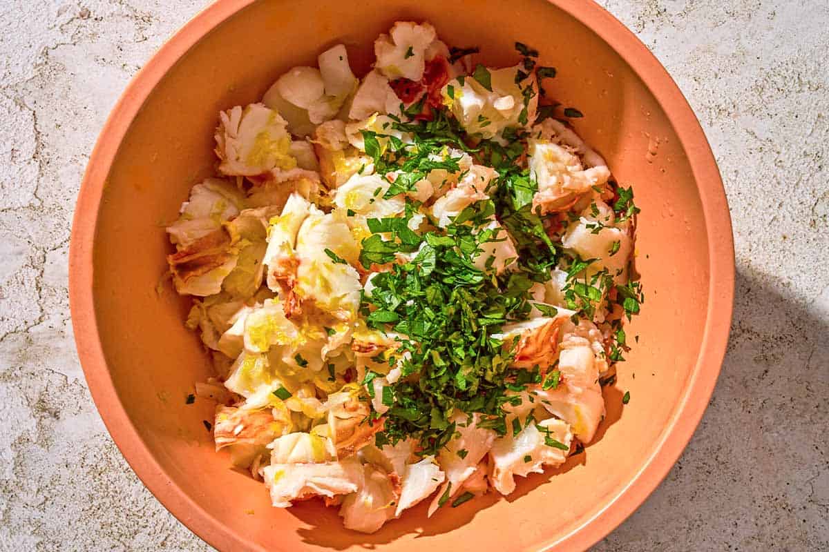 La chair de homard, le zeste de citron et le persil pour les pâtes au homard dans un bol.