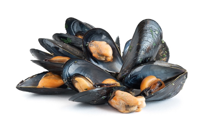 groupe de moules bouillies avec de l'ail et du persil isolé sur fond blanc