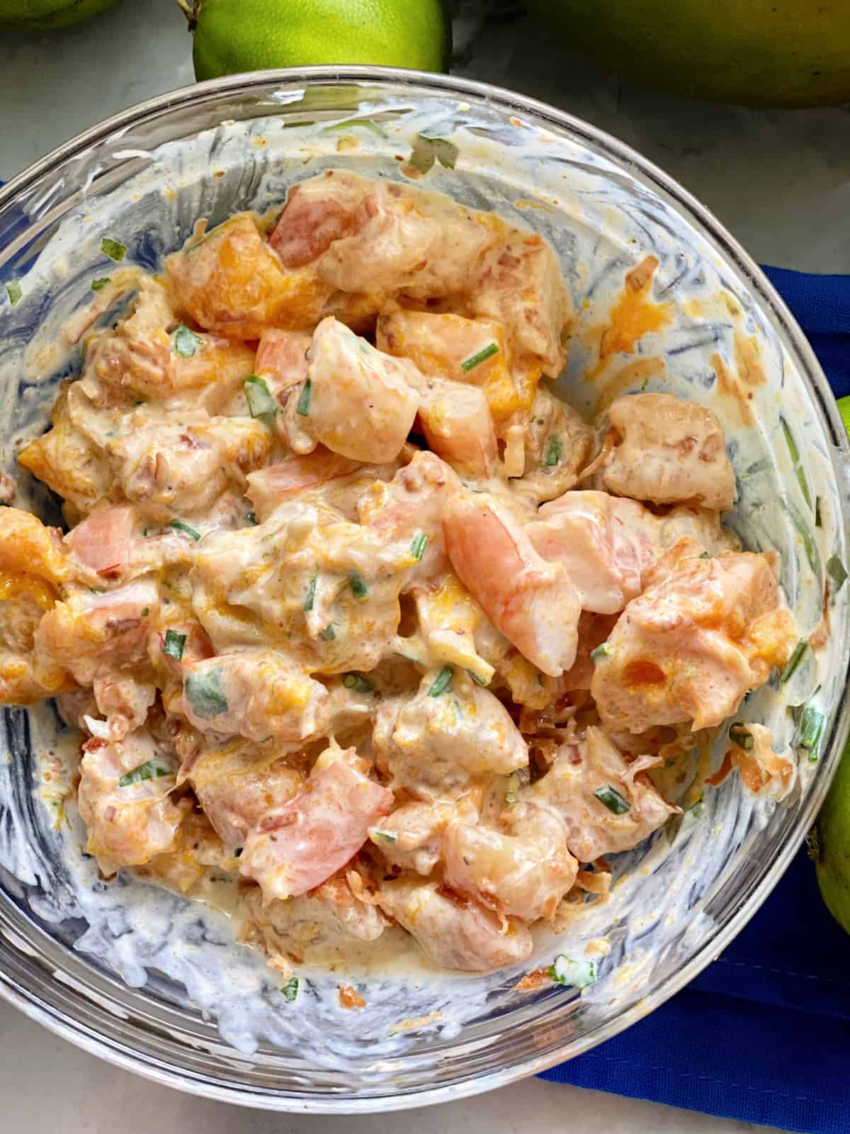 Vue de dessus d'un bol en verre de crevettes avec sauce et mangue.