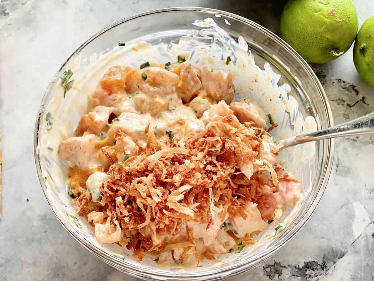 Vue de dessus d'un bol en verre rempli de salade de crevettes et de noix de coco grillée.