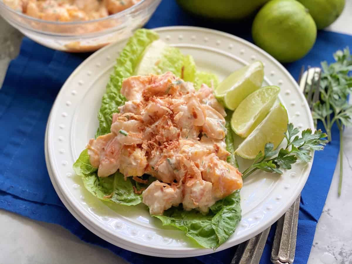 Assiette blanche avec feuilles de laitue et crevettes en sauce.