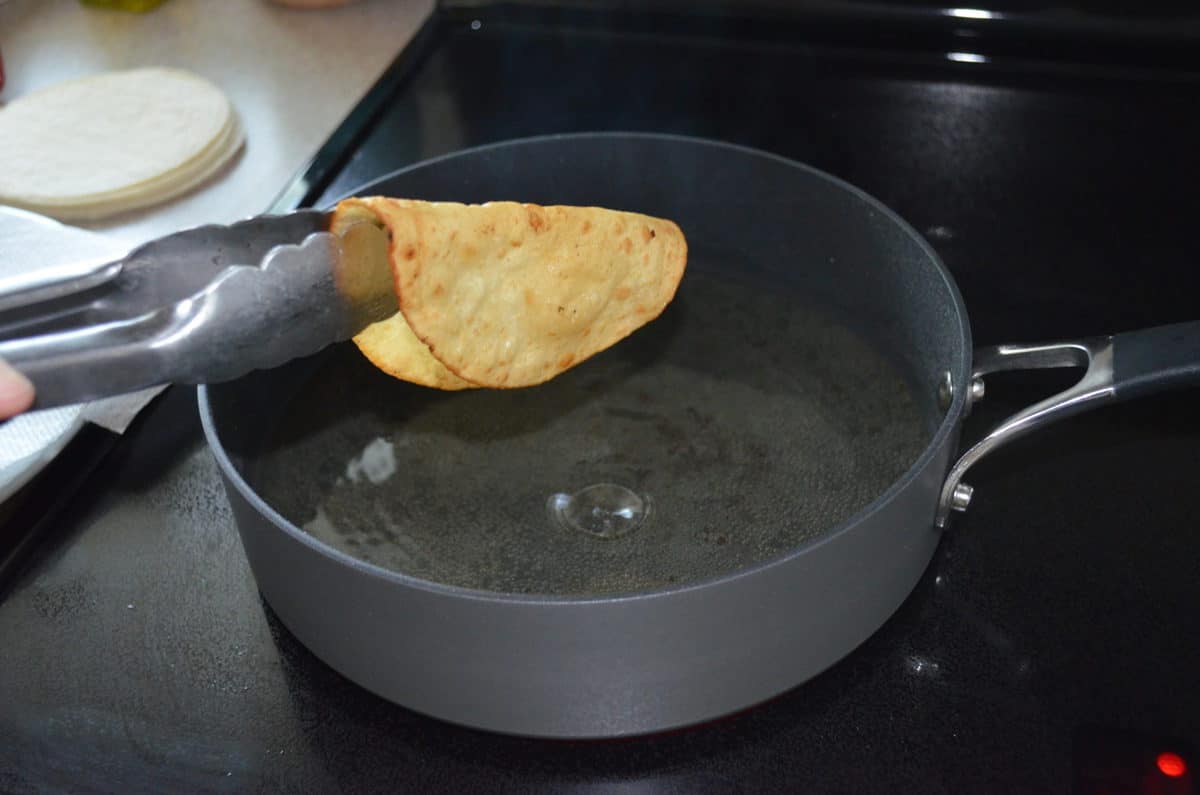 langues tenant la tortilla molle sur une poêle d'huile chaude avant de durcir la coque.