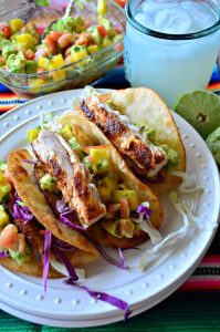 closeup Fish Tacos with Mango Avocado Salsa with a margarita and avocado mango salsa in the background.