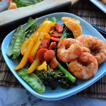 Assiette carrée avec crevettes, brocolis, poivrons, carottes et petits pois.