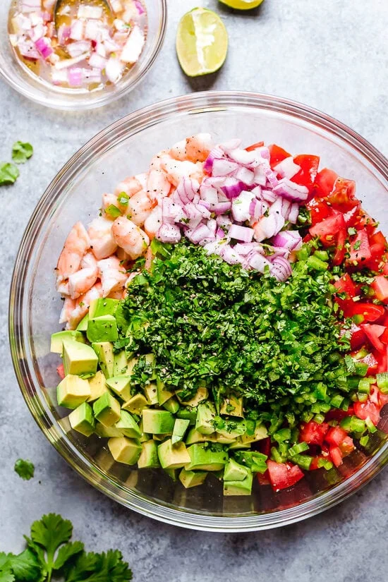 Ingrédients de la salade de crevettes et d'avocat avec tomates et coriandre, dans un bol.