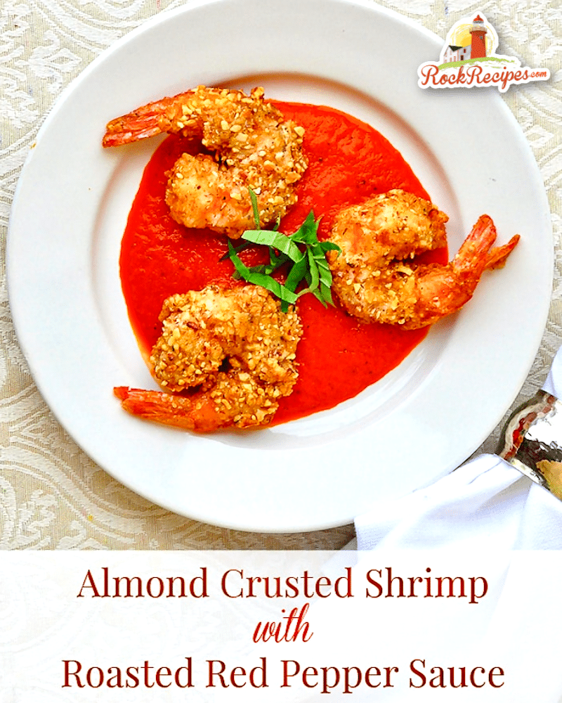 Image de crevettes en croûte d'amandes avec sauce aux poivrons rouges rôtis avec texte de titre ajouté pour les publications sur les réseaux sociaux.