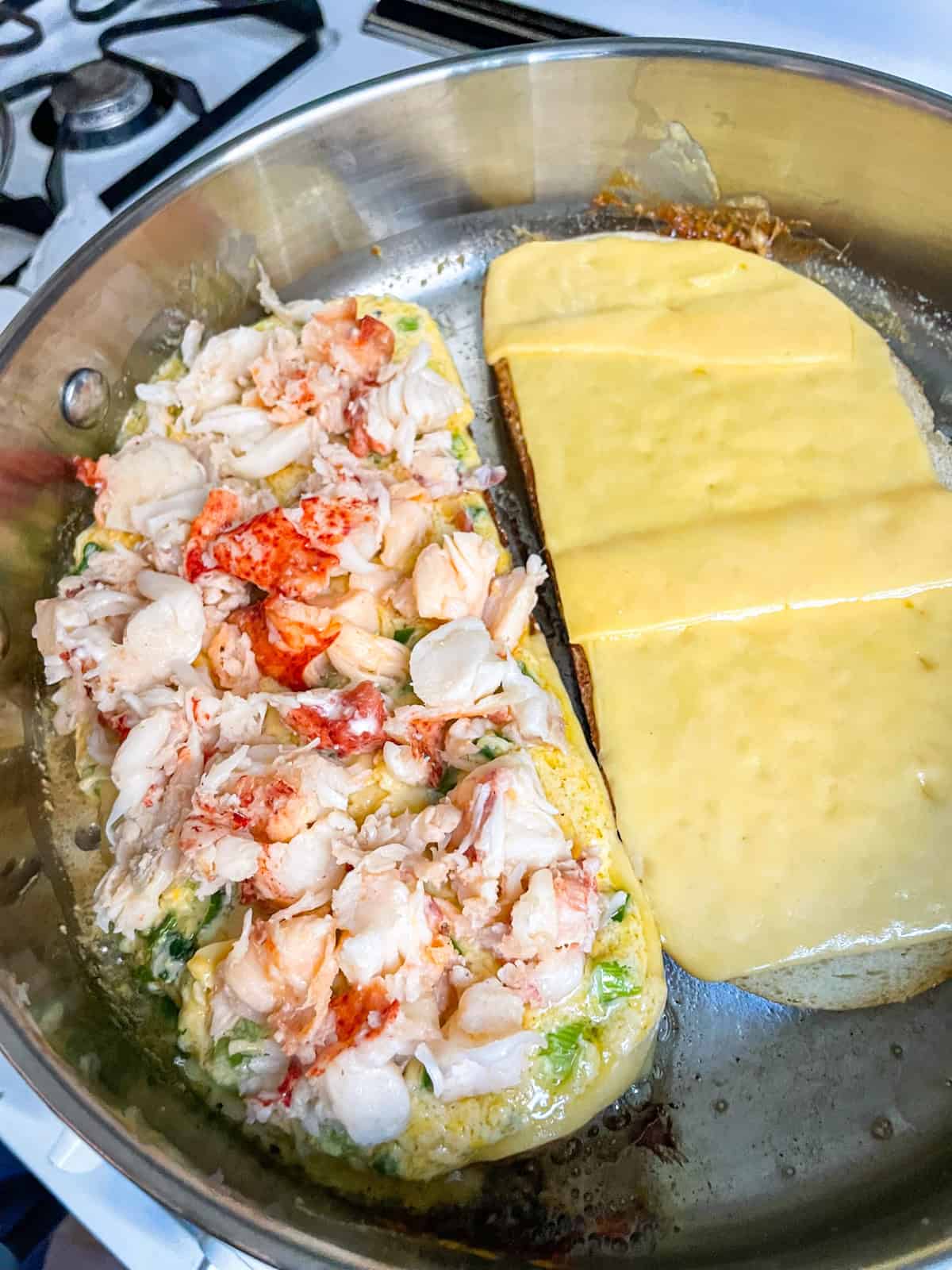 Homard, mélange et fromage disposés sur du pain dans une poêle.