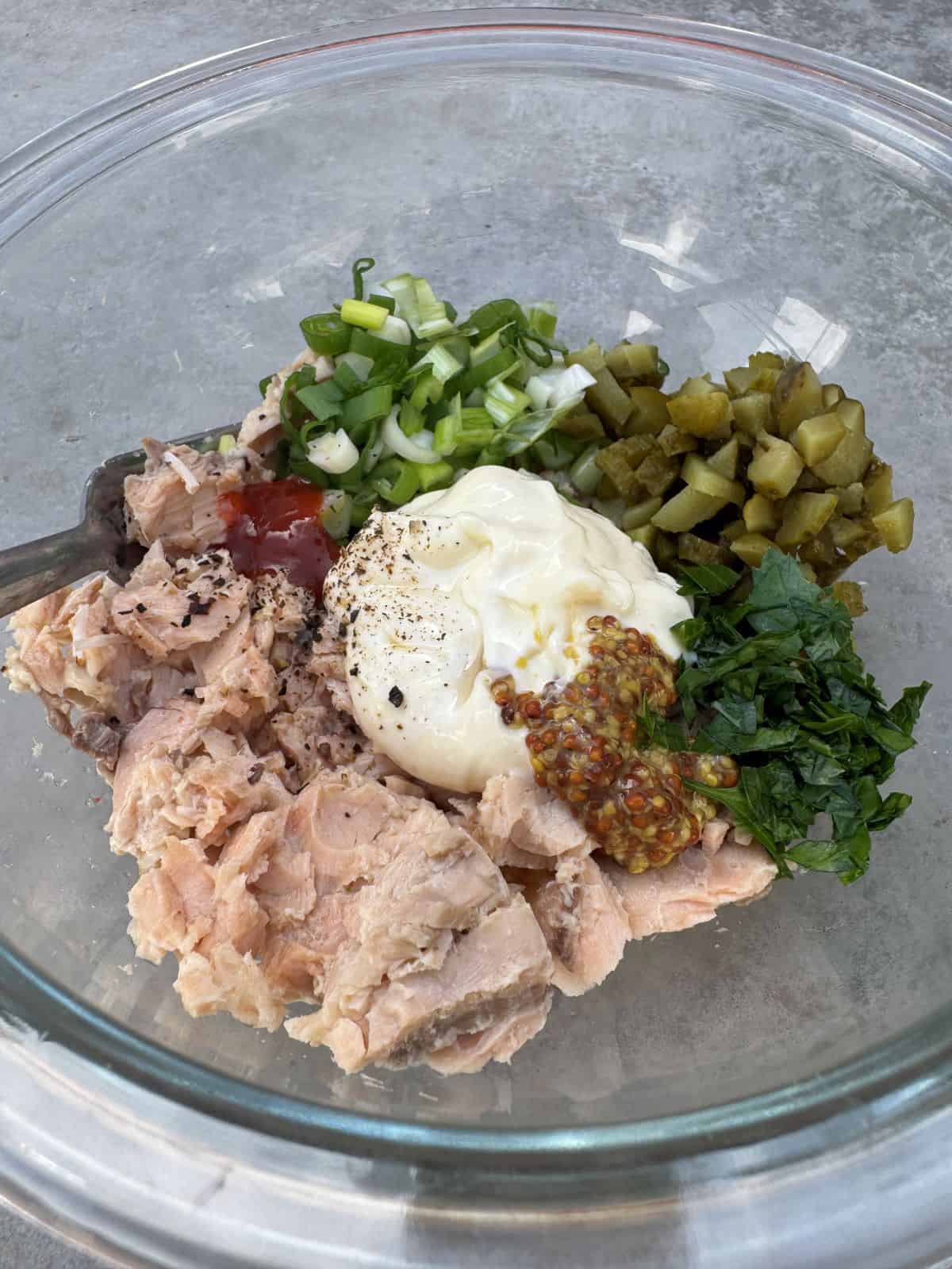 ingrédients pour faire une salade de saumon en conserve comme du saumon en conserve, des cornichons, de la mayonnaise, de l'oignon vert, de la moutarde, de la sauce piquante et du jus de citron