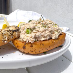 canned salmon salad recipe on a toasted bagel on a white place