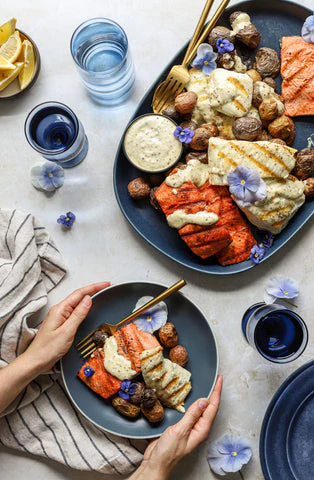 Du saumon rouge, du poisson blanc et une garniture de fleurs bleues trônent sur deux assiettes bleues dans cette recette parfaite pour la fête du 4 juillet.