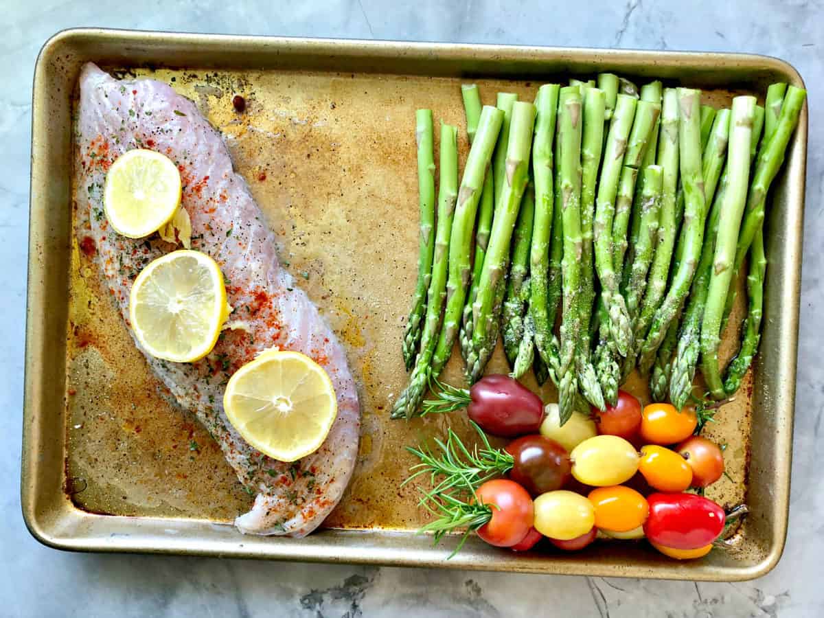 vue de dessus plaque à pâtisserie avec vivaneau non cuit, tomates raisins et asperges.