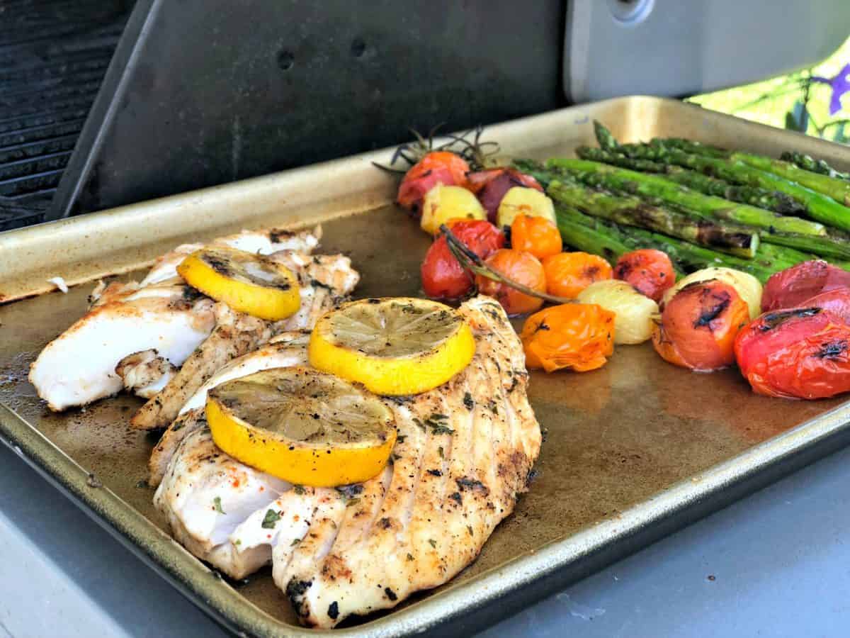 plaque de cuisson avec du poisson grillé garni de rondelles de citron, de tomates raisins et d'asperges avec le texte du titre.